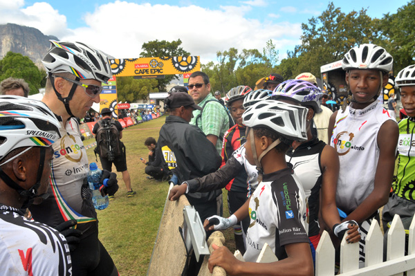 Christoph Sauser and team mate Sipho Modalo with a group of Kaymandi children at the finish of stage 6 of the 2016 ABSA Cape Epic. Photo: Dino Lloyd